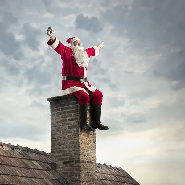 Julemanden sidder på en skorsten og vinker